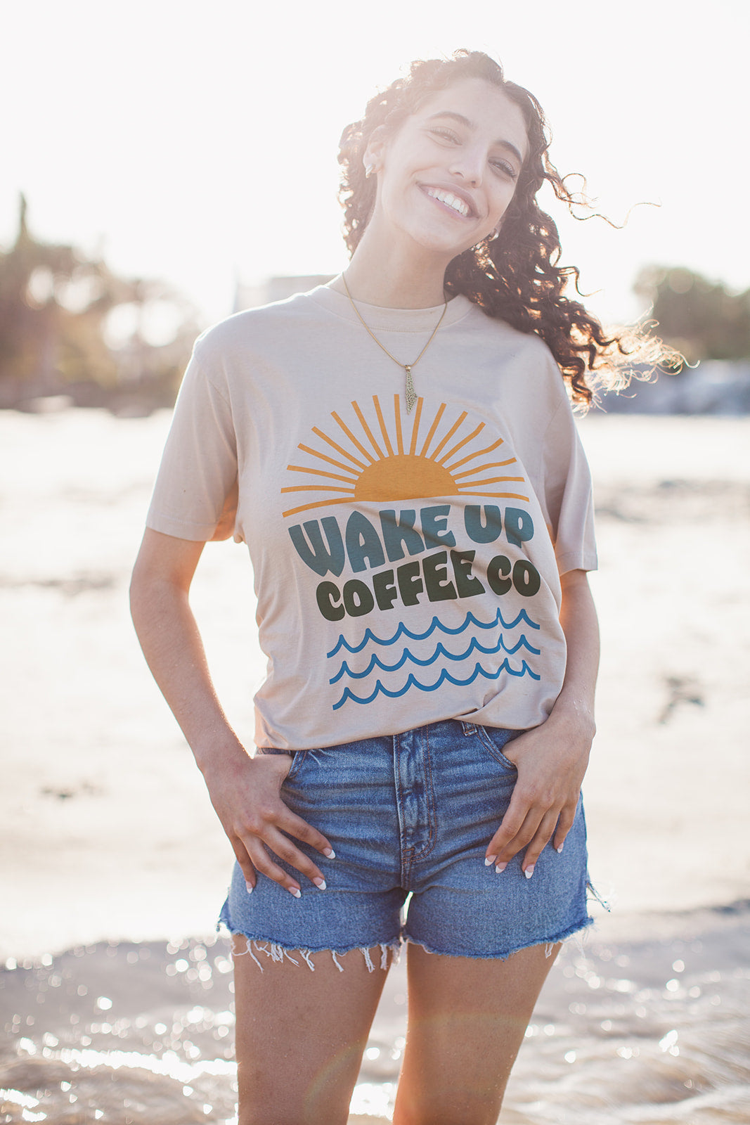 A person in a turquoise Wake Up tee enjoying coffee outdoors