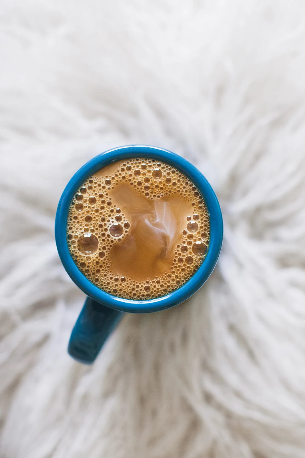 A freshly brewed coffee with cream and sugar in a blue Wake Up mug