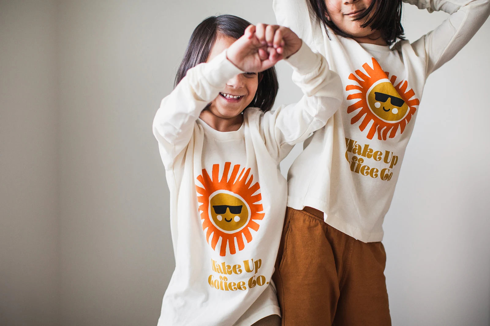 Two people wearing Wake Up Coffee sunshine sweatshirts